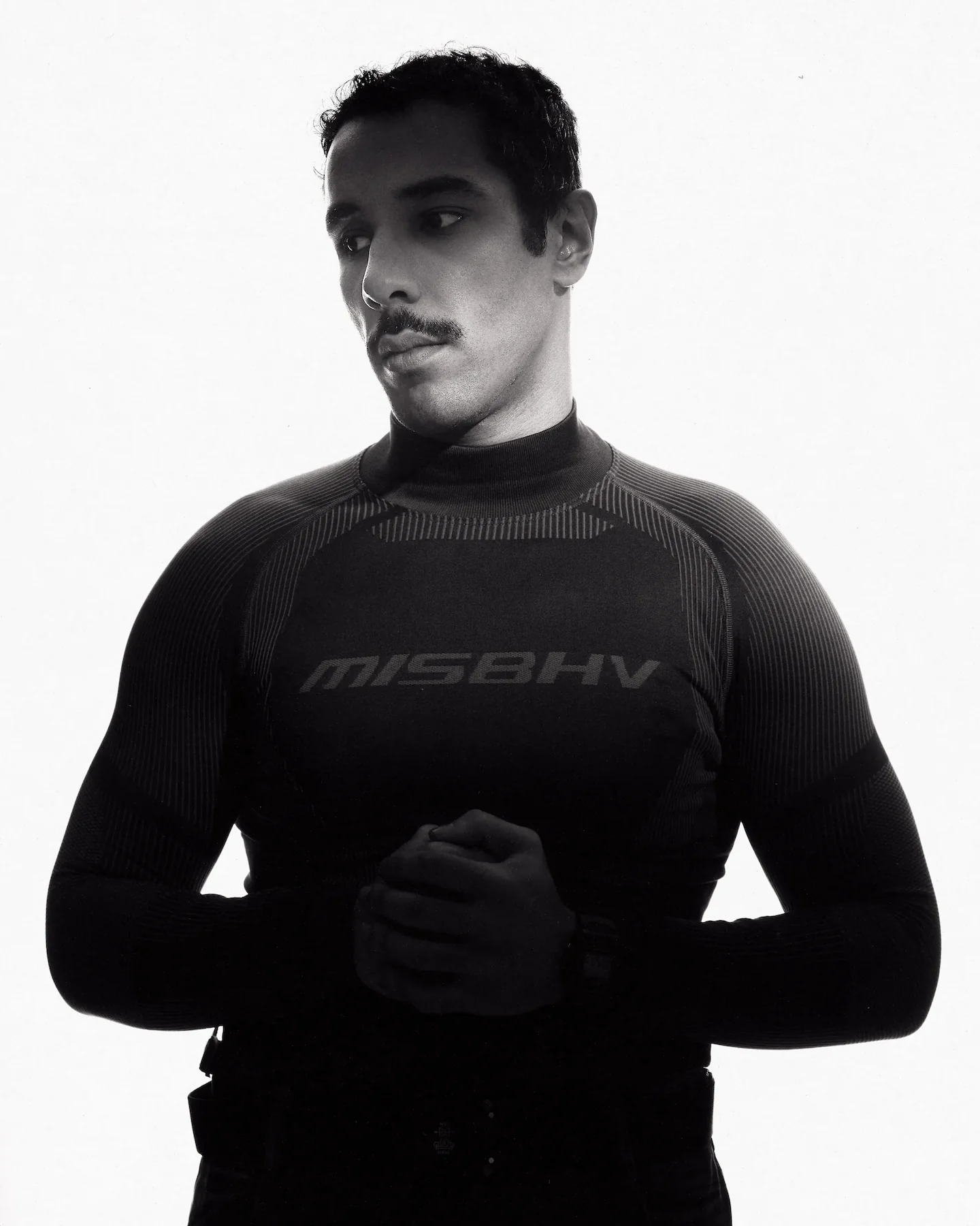 M Le Maudit in a black MISBHV top, hands clasped, on a white background