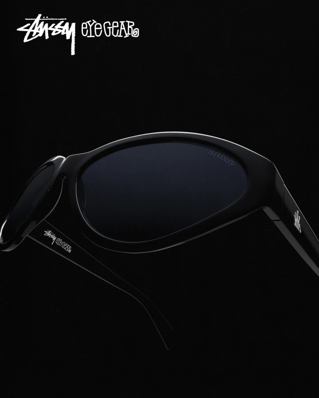 Black Stüssy Eyegear sunglasses close-up on black, Stüssy Eyegear logo in the corner