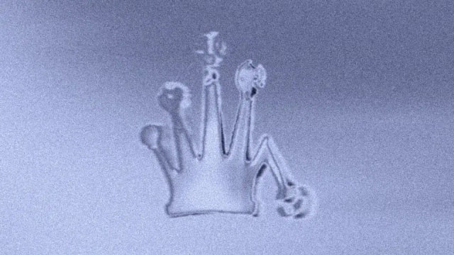 Stüssy crown and 8-ball embossed in a pale blue surface, still from the 3D film