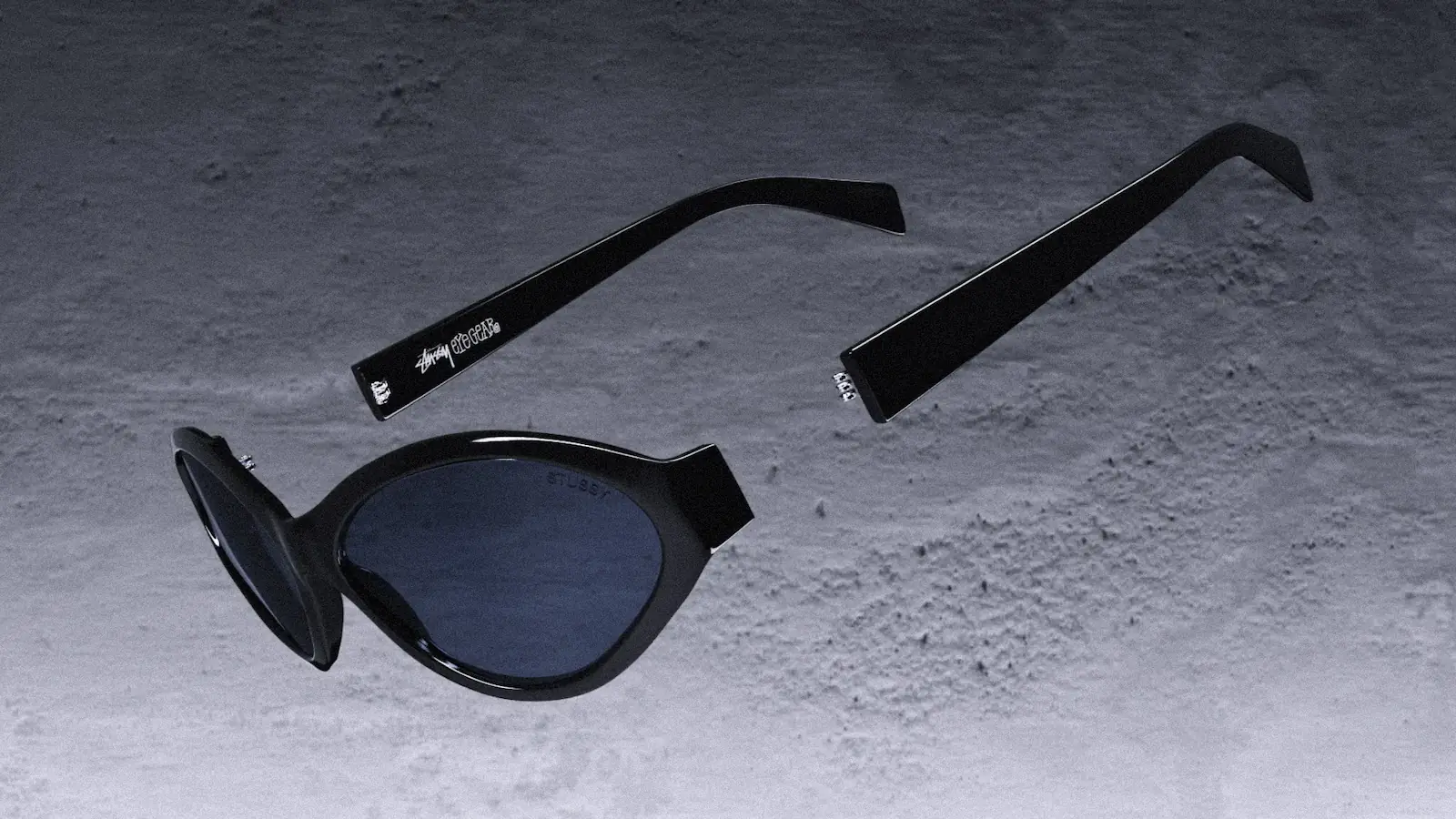 Black Stüssy Eyegear sunglasses floating apart above a concrete floor, still from the 3D film