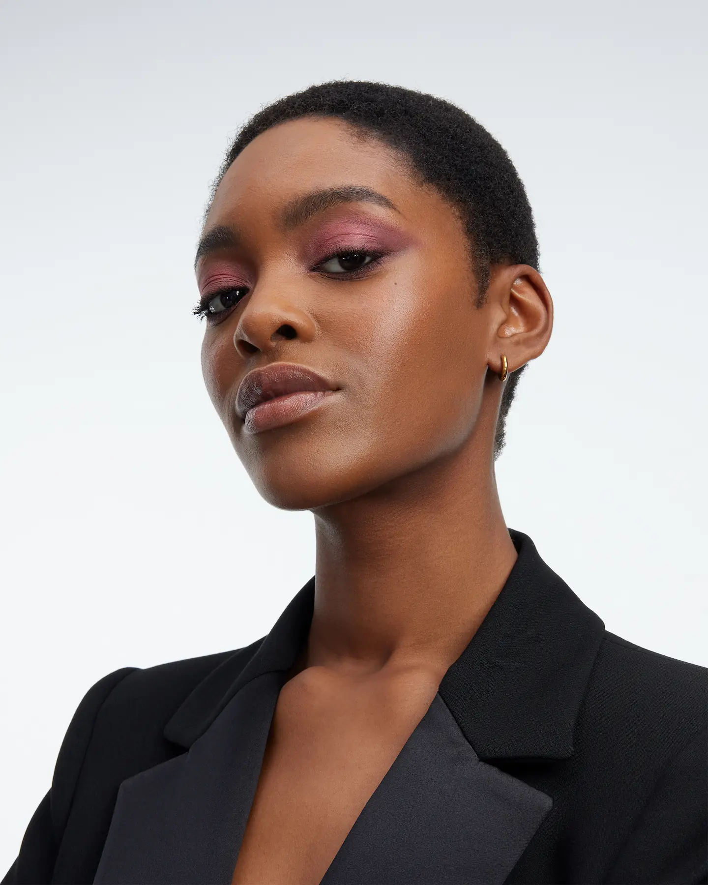 YSL Beauty portrait, model with very short hair and plum eyeshadow in a black blazer