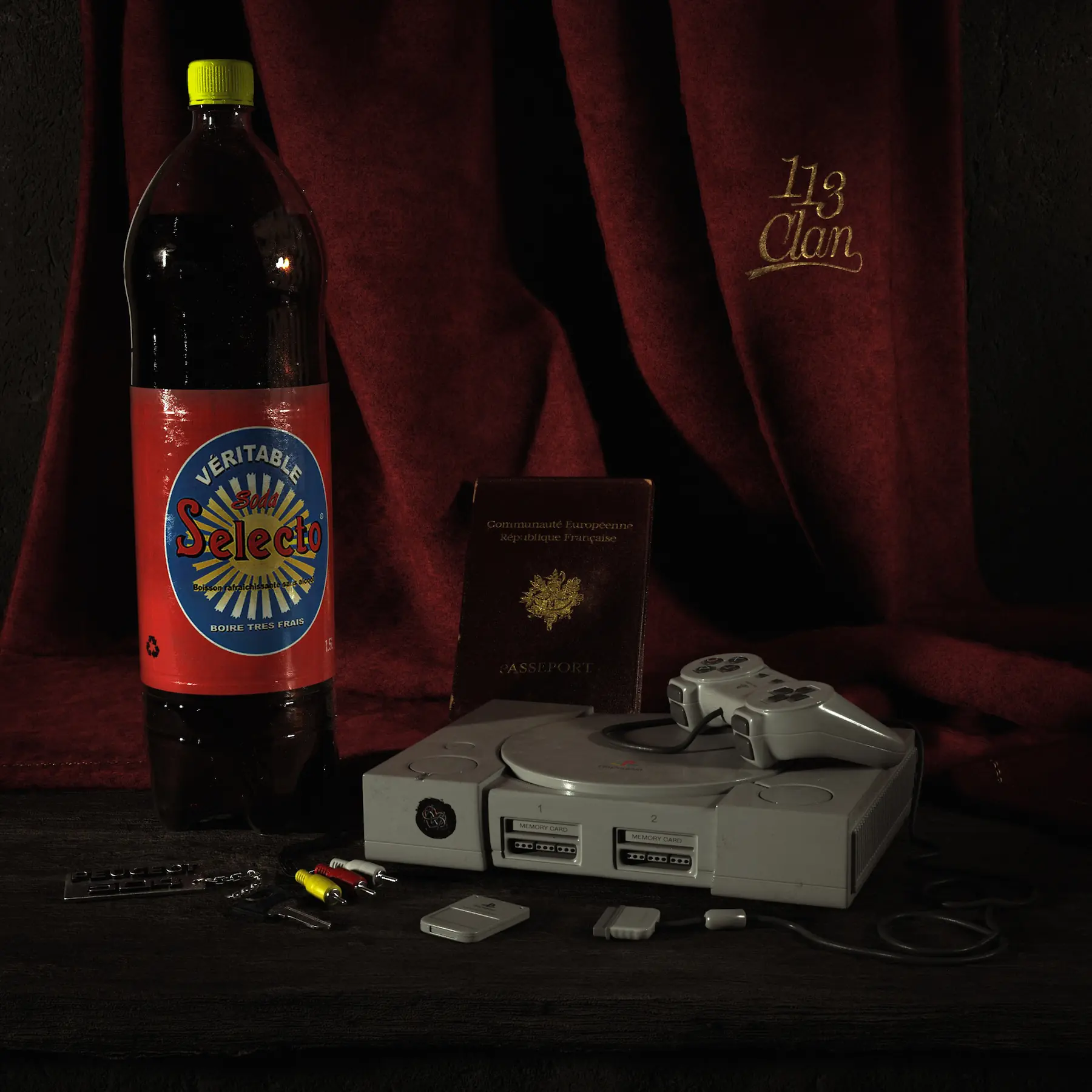 3D still life: Selecto soda bottle, original PlayStation and controller, French passport, red curtain marked 113 Clan